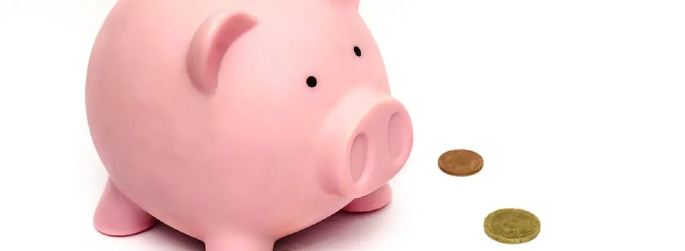 pink piggy bank with coins all around it.